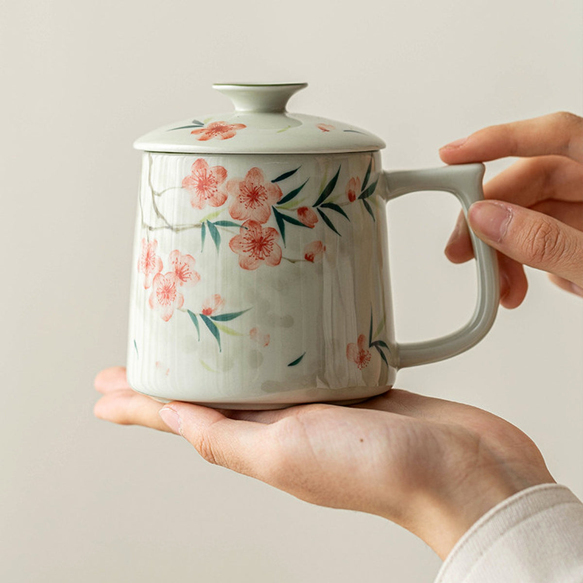 Hand-painted peach blossom ceramic mug with lid and tea strainer, plant ash glaze, styled in a home setting