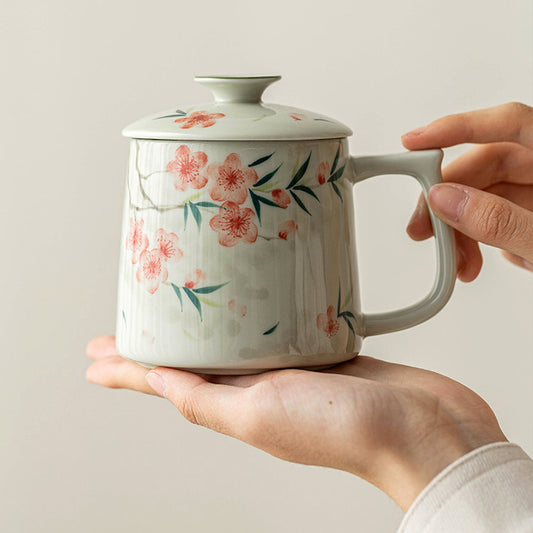 Hand-painted peach blossom ceramic mug with lid and tea strainer, plant ash glaze, styled in a home setting